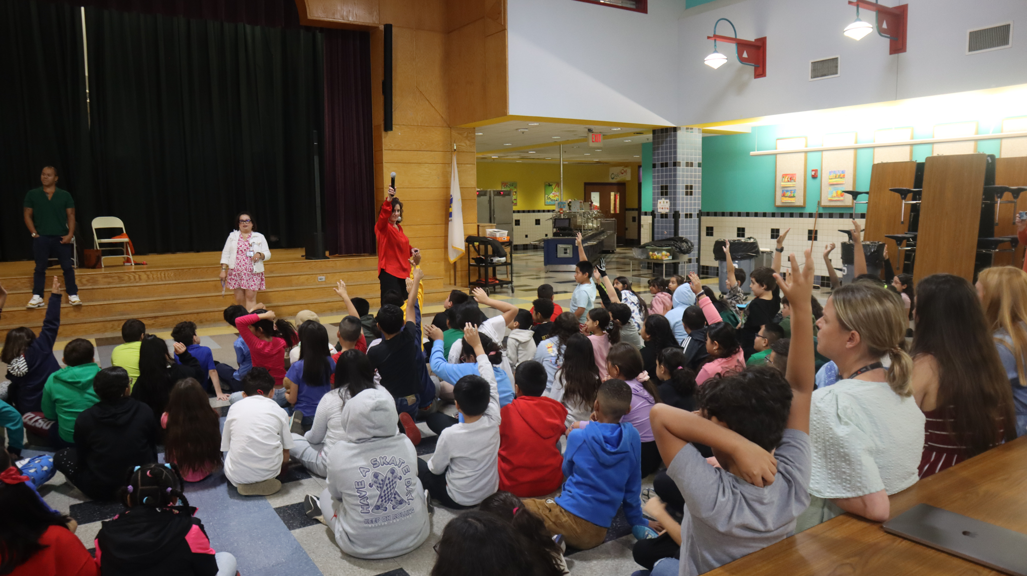 Students raising their hands to answer a question at the White Cane Safety Awareness Assembly